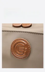 Detailed close-up of a brown leather logo patch on a durable nylon commuter backpack