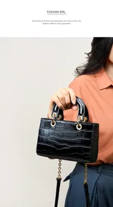 Détail d'un sac à main en cuir noir façon crocodile avec garnitures dorées et bandoulière