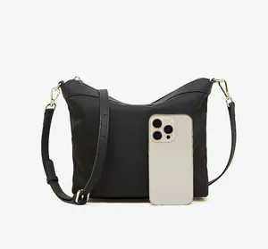 Detail view of black nylon leather shoulder bag with gold hardware and phone for size