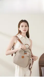 Nylon backpack with leather trim and round logo patch shown on a model