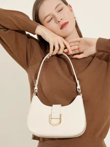 Elegante cremefarbene Hobo-Bag mit goldener Hardware, präsentiert von einem Modell im Studio