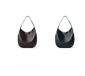 Detail of minimalist leather hobo bags in coffee and black with crescent moon silhouette