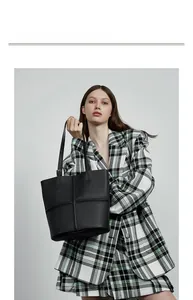Fashion model styling a black pebbled leather bucket bag with cross stitching details