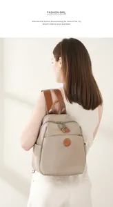 Detail of khaki oxford and leather backpack on model featuring a round logo and side pockets