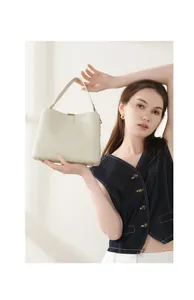 Dettaglio borsa a secchiello in pelle martellata beige con finiture dorate e piedini