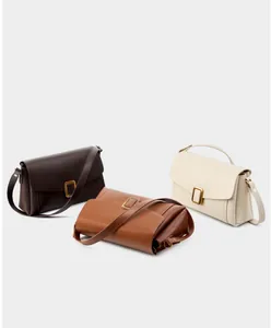 Detailed view of three minimalist leather handbags in brown, tan, and beige with metal buckles