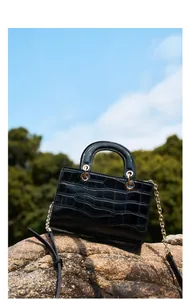 Détail macro de la texture crocodile noire et chaîne dorée sur un sac à main chic