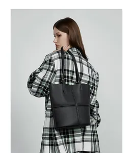 Chic black pebbled leather tote bag styled with a plaid blazer for a professional look