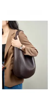 Side view of a large dark brown leather tote bag with lychee grain texture on a model