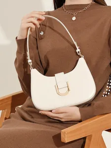 Schultertasche aus elfenbeinfarbenem Leder mit goldener Hufeisenschnalle an einem Model