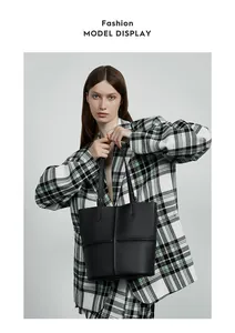 Detail of black pebbled leather tote bag with cross-stitch seam held by fashion model