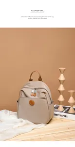Detail of oxford fabric backpack showing leather logo, double zippers and side pockets