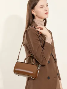 Chic brown leather cylindrical bucket bag with top handles and adjustable shoulder strap
