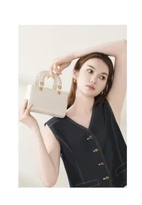 Détail d'un sac à main en cuir crème avec texture croco et anneaux en métal doré