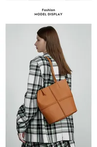 Detailed close-up of brown pebbled leather tote bag with cross-stitch design details