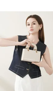 Sac à main élégant en cuir blanc crème avec motif crocodile tenu par un mannequin chic