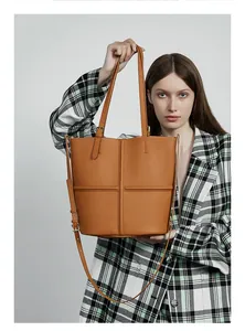 Close-up of caramel leather tote bag with cross stitching and adjustable shoulder strap
