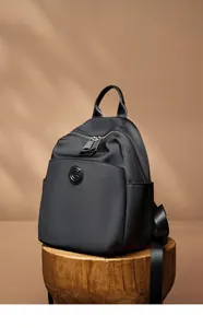 Detail of black oxford fabric backpack with leather accents and circular G logo emblem