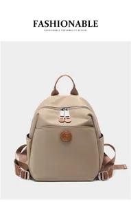 Detail view of khaki nylon backpack with brown leather accents and circular G logo badge