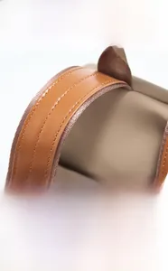 Close-up of brown leather handle with double stitching on khaki nylon backpack fabric