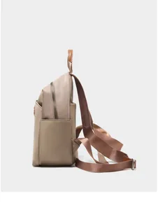 Side view of beige nylon and leather backpack with side pockets and wide webbing straps
