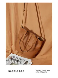 Detail of warm brown saddle tote bag with cross-strap design and soft leather texture