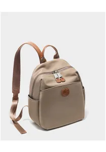 Detail view of khaki nylon backpack featuring brown leather trim and circular logo