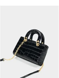 Détail du sac en cuir noir à motif crocodile avec bandoulière chaîne dorée polie