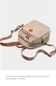 Detail view of khaki waterproof nylon backpack with brown leather trim and metal zippers