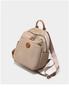 Detail view of khaki Oxford fabric backpack with leather handles and multi-pocket design