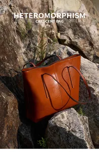 Macro shot of caramel brown leather tote with crescent shape on textured rock