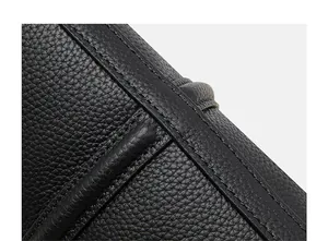 Close-up of litchi grain black leather texture and fine stitching on a luxury tote bag