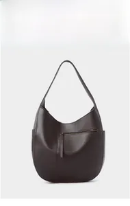 Detail of dark brown pebble leather hobo bag showing side pocket and zipper texture
