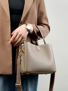 Borsa a mano in pelle martellata talpa con dettagli dorati e tracolla larga su modella