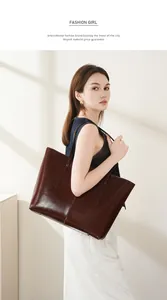 Detailed view of large dark brown leather tote bag with glossy wax finish and metal rivets