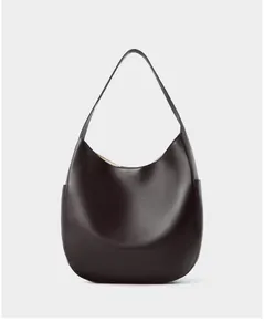 Detailed macro view of premium pebble grain leather texture on a deep brown hobo bag