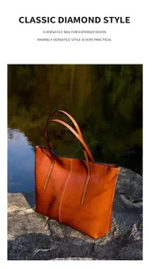 Detailed view of caramel leather tote bag with vertical stitching against a lake backdrop