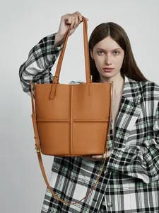 Large caramel leather bucket tote bag with cross-stitch detail and adjustable strap