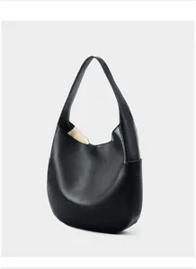 Detail of black pebble leather hobo bag showing refined texture and crescent shape