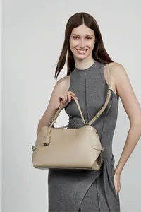 Mannequin portant un sac seau beige en cuir avec poignée et bandoulière amovible