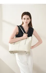 Detail of cream leather tote bag featuring bottom protective metal studs and rich texture