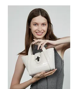 Dettaglio di una borsa bianca in pelle con stampa coccodrillo e chiusura a girello in metallo