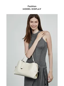 Détails du sac à main en cuir crème avec boucles argentées et fine poignée sur modèle