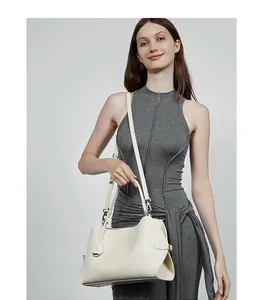 Détail du sac cabas en cuir crème avec bandoulière réglable et boucle latérale en métal