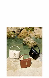 Detailed view of leather crossbody bags in white, black, and brown with gold locks