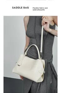 Détail du sac selle en cuir blanc cassé avec ferrures argentées et double bandoulière