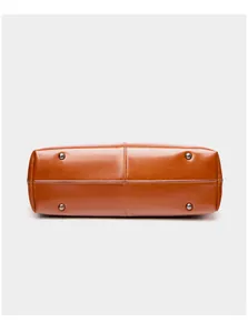 Detailed base of the leather tote bag showing four silver protective metal feet studs