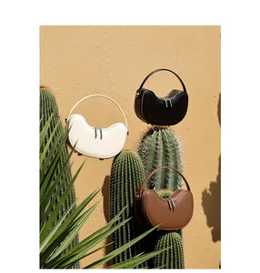 Three leather crescent bags in black, white, and brown with unique circular handles