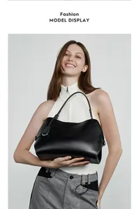 Sac bandoulière tendance en cuir noir à longues anses présenté par un mannequin