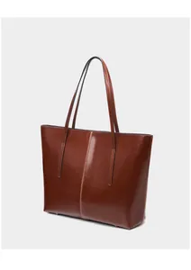 Detail view of brown leather tote showing sleek glossy finish and protective metal feet